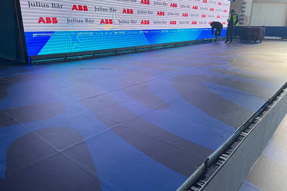 Formula E Branding Berlin 2023: Bühne mit Sponsorenlogos und Technikern.