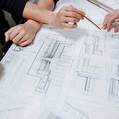 Textile Architektur Beratung: Architektenhände mit Bauplan und Stift.