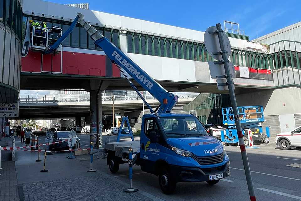 Branding Steg Erdberg: Arbeiter an Wiener Linien Brücke mit Felbermayr Hebebühne. Plakativ.