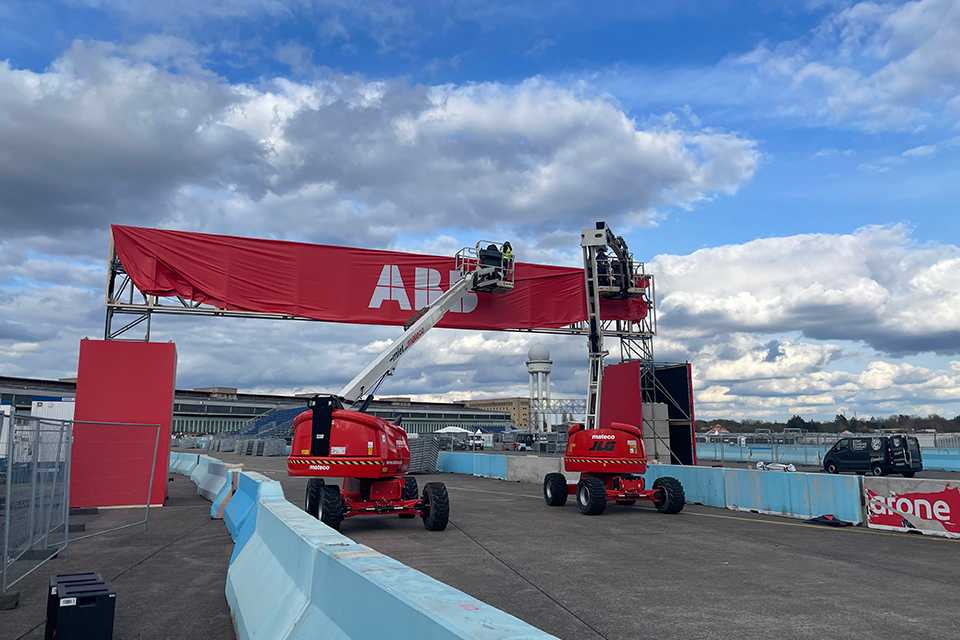 Branding für Formula E Berlin 2023: Monteure installieren ABB-Banner mit Hebebühnen.