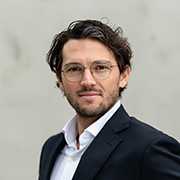 Mag. Manuel Bellutti, Porträt. Mann mit Brille und Anzug.
