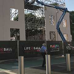 Baustelle: Bauzaun sichert Baustelle mit Gerüst und Hebebühne. Life Ball Banner im Vordergrund.