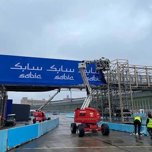 Branding für Formula E Berlin 2023: Rote JLG-Hebebühnen vor Sabic-Banner auf der Rennstrecke.