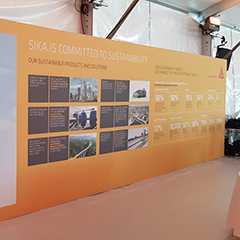 Sika Indoor Event: Nachhaltigkeitsprojekte und Lösungen auf gelbem Hintergrund.