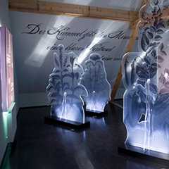 Ausstellungen: Kunst und Kultur. Beleuchtete Skulpturen vor Wand mit Schriftzug. Kunstausstellung.