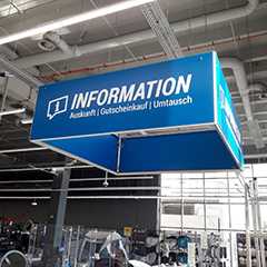 Deckenhänger im Geschäft: Blaues Information-Schild für Auskunft, Gutscheinkauf und Umtausch.