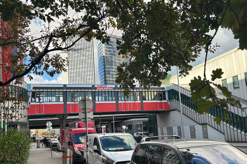 Wiener Linien Steg Erdberg: Rote Straßenbahn auf Brücke, Gebäude im Hintergrund.
