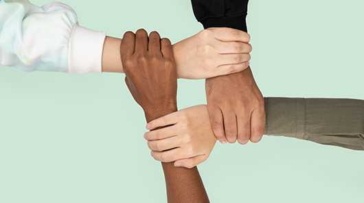 Hände verschiedener Hautfarben, die ein Team bilden. Diversität im Team.