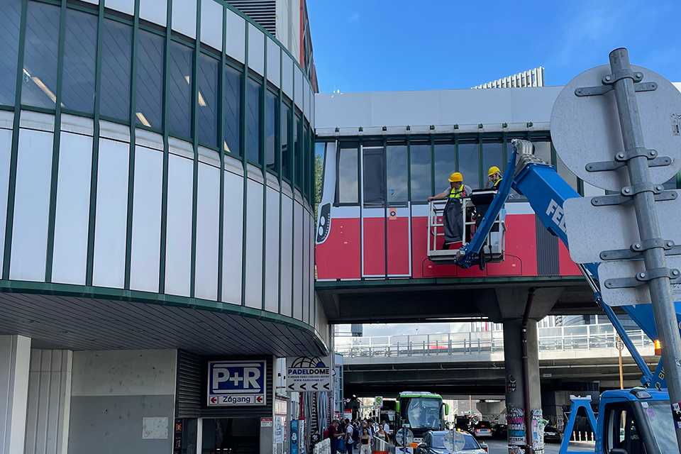 Branding Steg Erdberg: Wiener Linien Werbung am Steg mit Arbeiter auf Hebebühne.