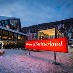 Leuchtlogo: House of Switzerland Geschäft im Schnee. Schweizer Laden mit rotem Logo.