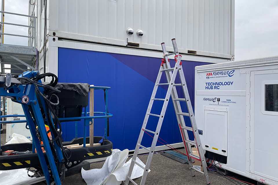 Branding Formula E Berlin 2023: Leiter und Hebebühne vor blauem Container mit Logo.