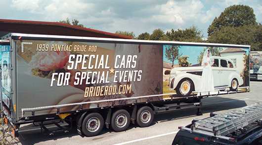 Gebäude & Fahrzeuge: LKW-Anhänger mit Werbung für Oldtimer-Vermietung. Pontiac Brautauto für Events.
