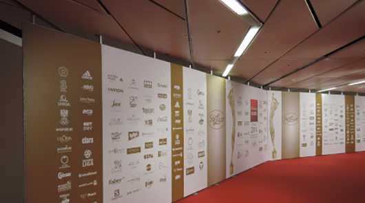 Messestand: Wand mit Logos und rotem Teppich. Firmenlogos auf Messe.