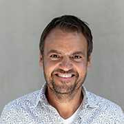 Bernhard Krätschmer Portrait. Lachender Mann mit Bart und gemustertem Hemd.