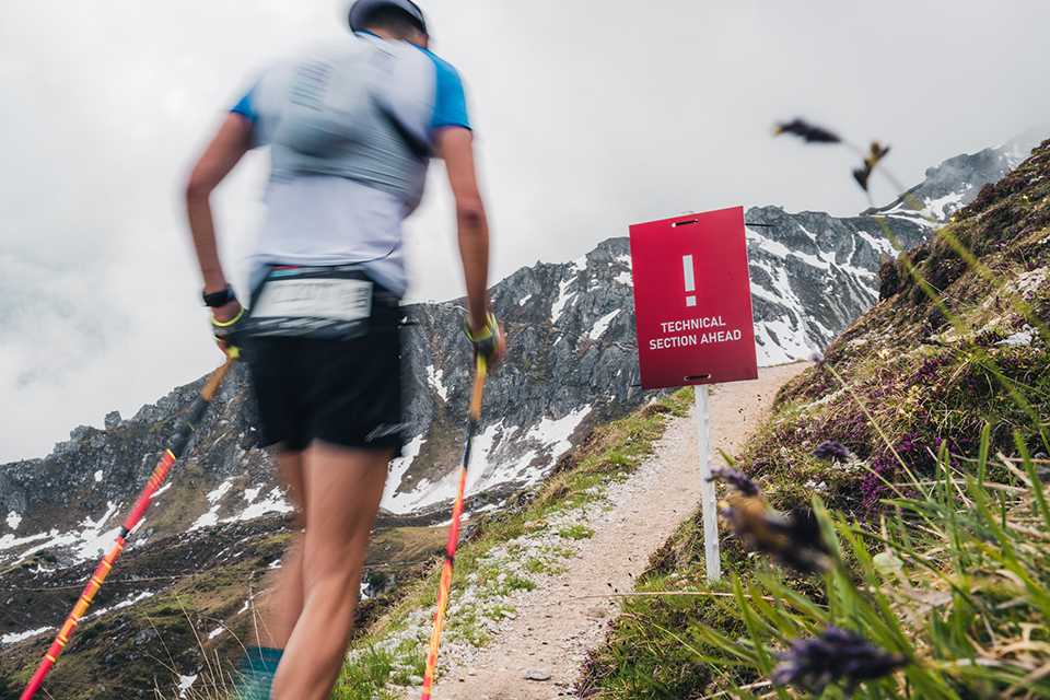 Trail Running WM Tirol 2023: Läufer auf Strecke mit Warnschild Technical Section Ahead.
