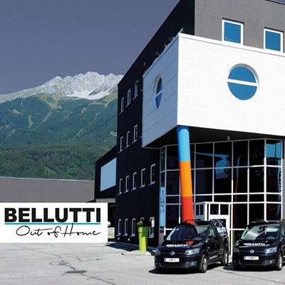 Bellutti Standort Innsbruck: Modernes Gebäude mit Firmenwagen und Bergkulisse.